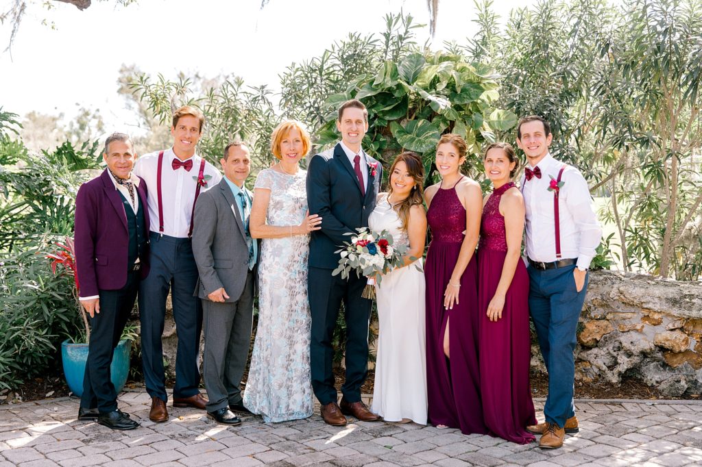 family photo of bride and groom at their wedding in Dubsdread Ballroom in Orlando Florida. Bride and Groom is in the middle of the photos while the Groom's immediate family surround them.