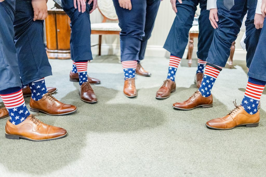 groomsmen showing off matching united states flag socks on the wedding day.