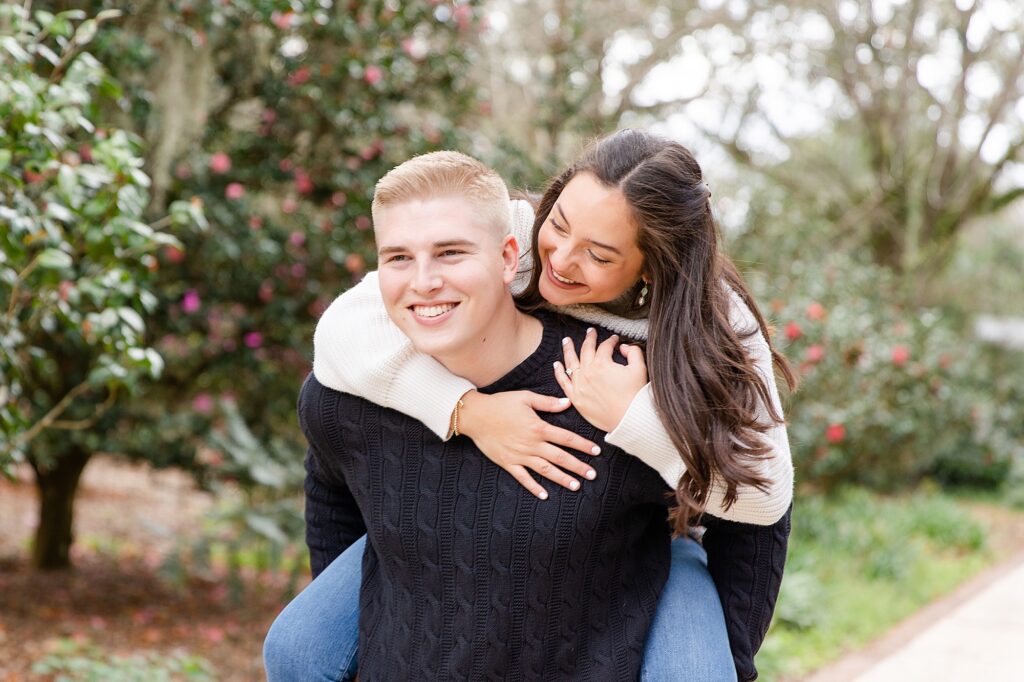 A young man takes his fiance on a piggyback ride during their engagement session in leu gardens. Taken my their Florida wedding photographer.