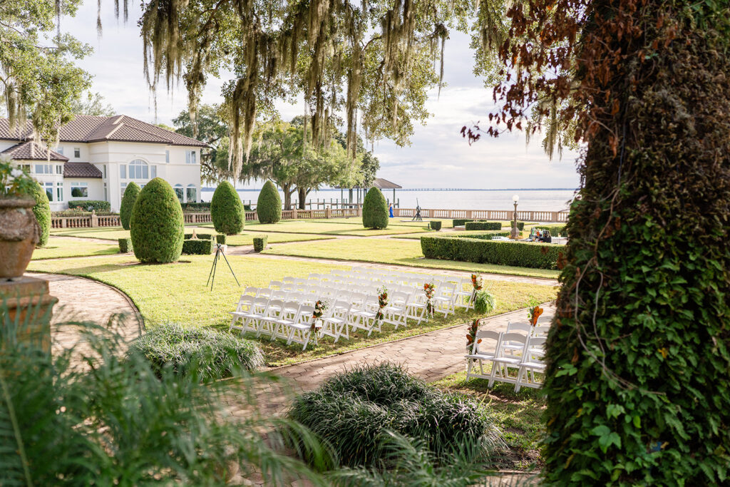 ceremony setup with white chairs outside of of Epping Forest Yacht Club Spanish-style wedding venue in Jacksonville, Florida, captured by Snapshots by Gabriela