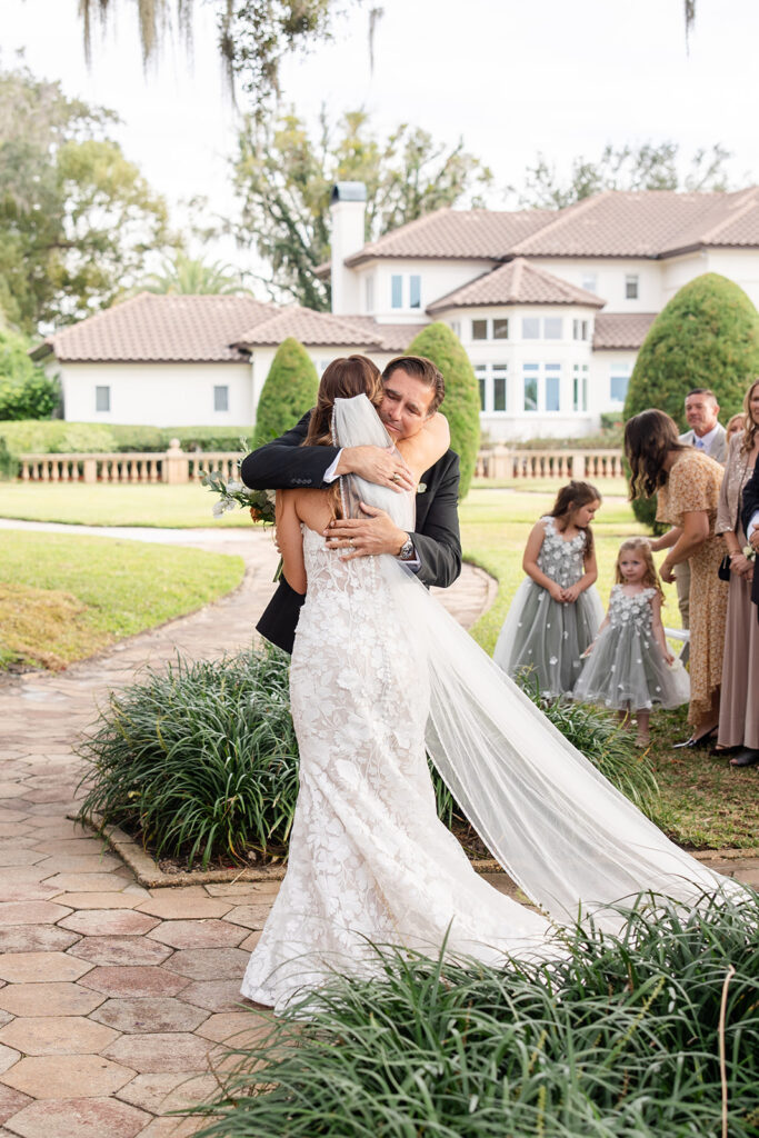 bride and her dad hug during an outdoor wedding ceremony at Epping Forest Yacht Club in Jacksonville, Florida, captured by Snapshots by Gabriela