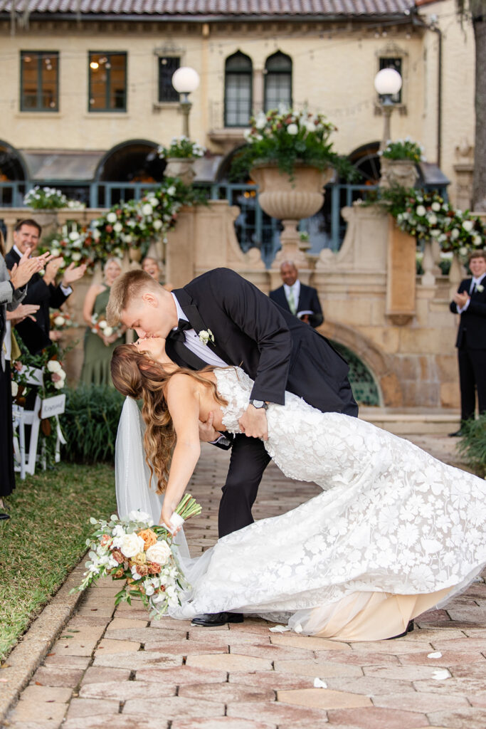 bride and groom dip and kiss during an outdoor wedding ceremony at Epping Forest Yacht Club in Jacksonville, Florida, captured by Snapshots by Gabriela
