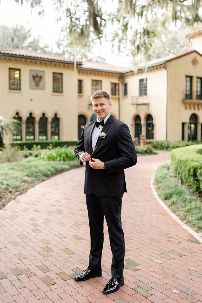 groom portrait in black tuxedo in front of the outdoor stone staircase at Epping Forest Yacht Club in Jacksonville, Florida, captured by Snapshots by Gabriela