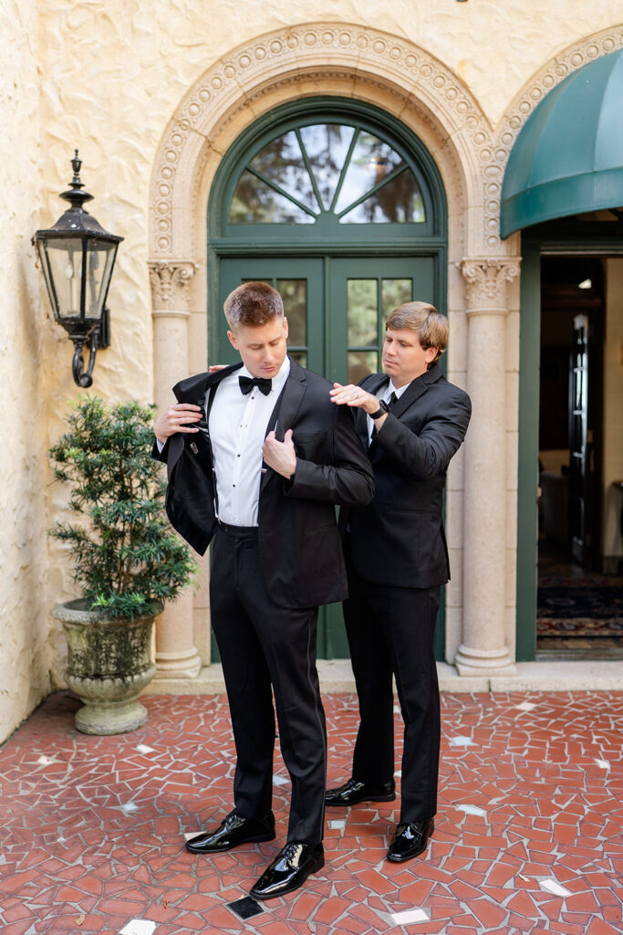 groom's father helping him put on his tuxedo jacket at Epping Forest Yacht Club in Jacksonville, Florida, captured by Snapshots by Gabriela