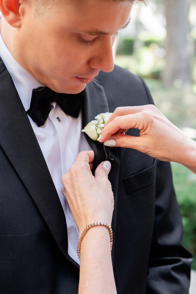 groom getting a boutonniere pinned on at Epping Forest Yacht Club in Jacksonville, Florida, captured by Snapshots by Gabriela