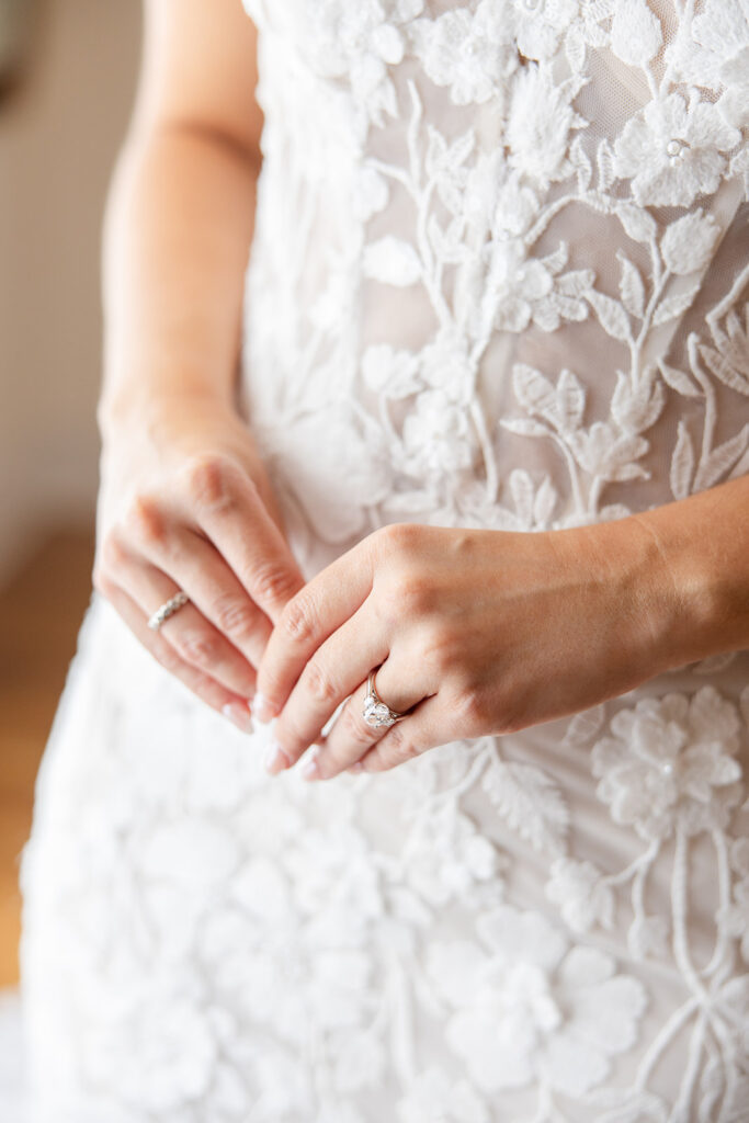 closeup of a bride's hands wearing a wedding ring and lace bridal gown at Epping Forest Yacht Club in Jacksonville, Florida, captured by Snapshots by Gabriela