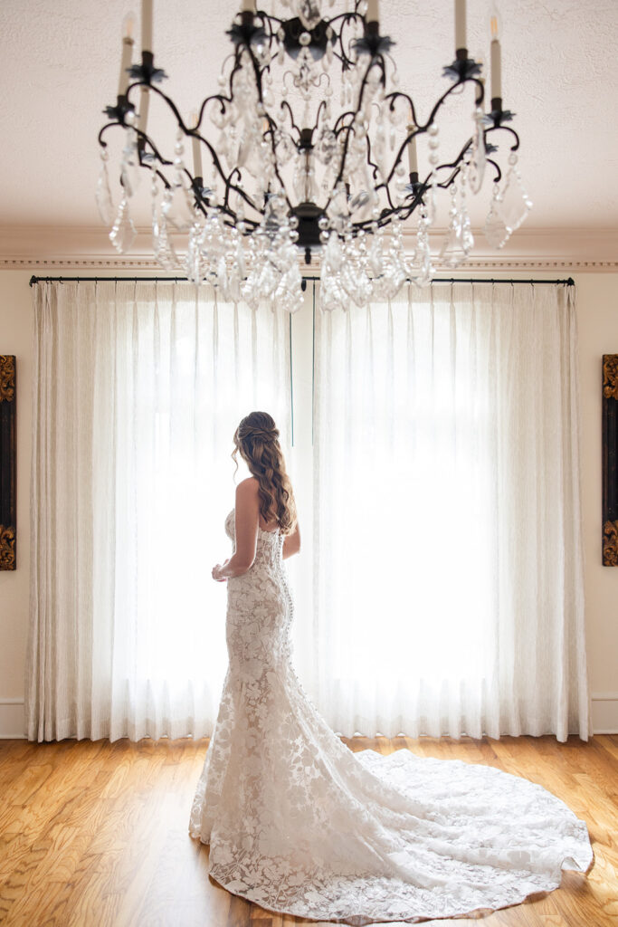bride in lace gown under a crystal chandelier at Epping Forest Yacht Club in Jacksonville, Florida, captured by Snapshots by Gabriela