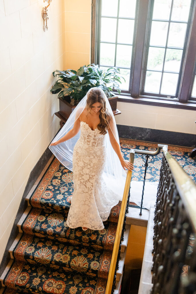 bride in lace dress going down carpeted stairs at Epping Forest Yacht Club in Jacksonville, Florida, captured by Snapshots by Gabriela