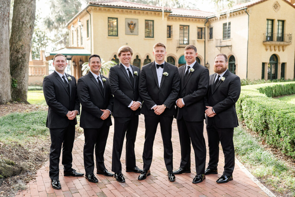 Wedding party portrait with groomsmen and groom wearing black tuxedos at Epping Forest Yacht Club in Jacksonville, Florida, captured by Snapshots by Gabriela