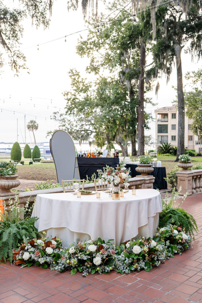 sweetheart table setup with fall florals surrounding it on the terrace at an outdoor wedding reception at Epping Forest Yacht Club in Jacksonville, Florida, captured by Snapshots by Gabriela
