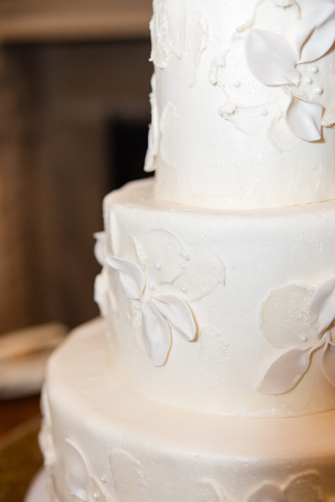 white three-tiered wedding cake with flowers at an outdoor wedding reception at Epping Forest Yacht Club in Jacksonville, Florida, captured by Snapshots by Gabriela