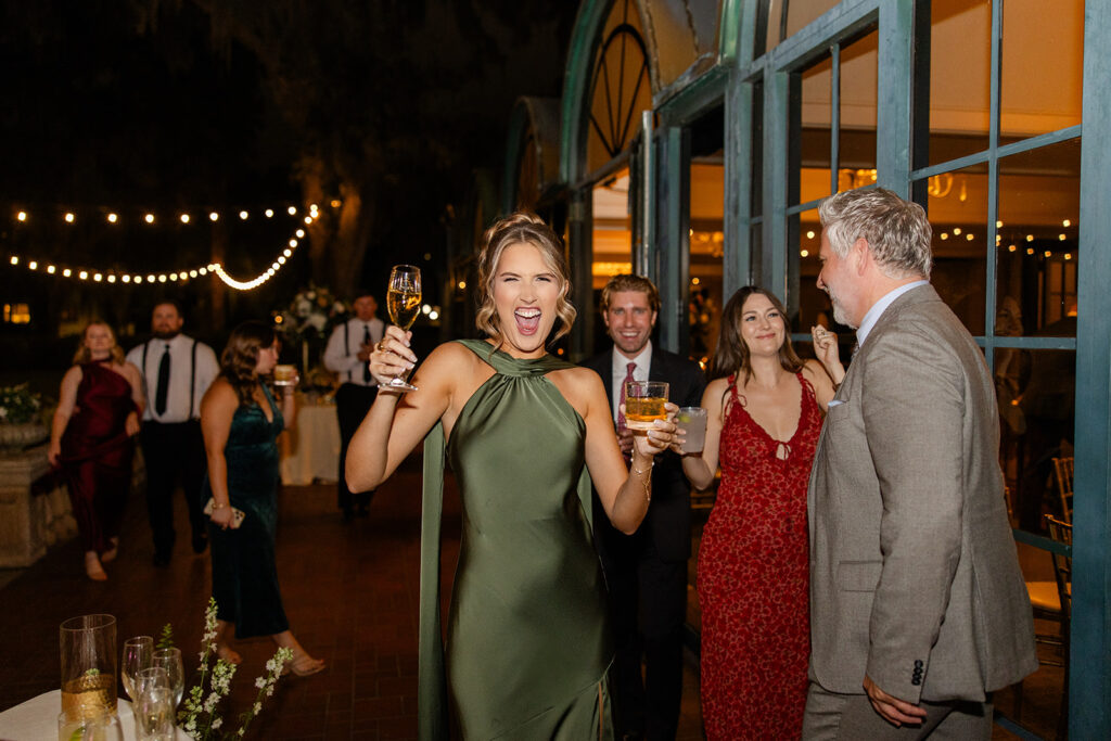 bridesmaid in green holding drinks at an outdoor wedding reception at Epping Forest Yacht Club in Jacksonville, Florida, captured by Snapshots by Gabriela