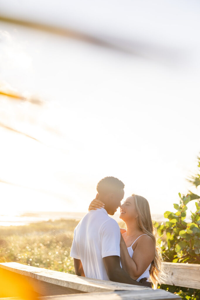 couple wearing white embrace against the sunrise in a beach engagement photo at Jetty Park Beach in Cape Canaveral, Florida, captured by Snapshots by Gabriela