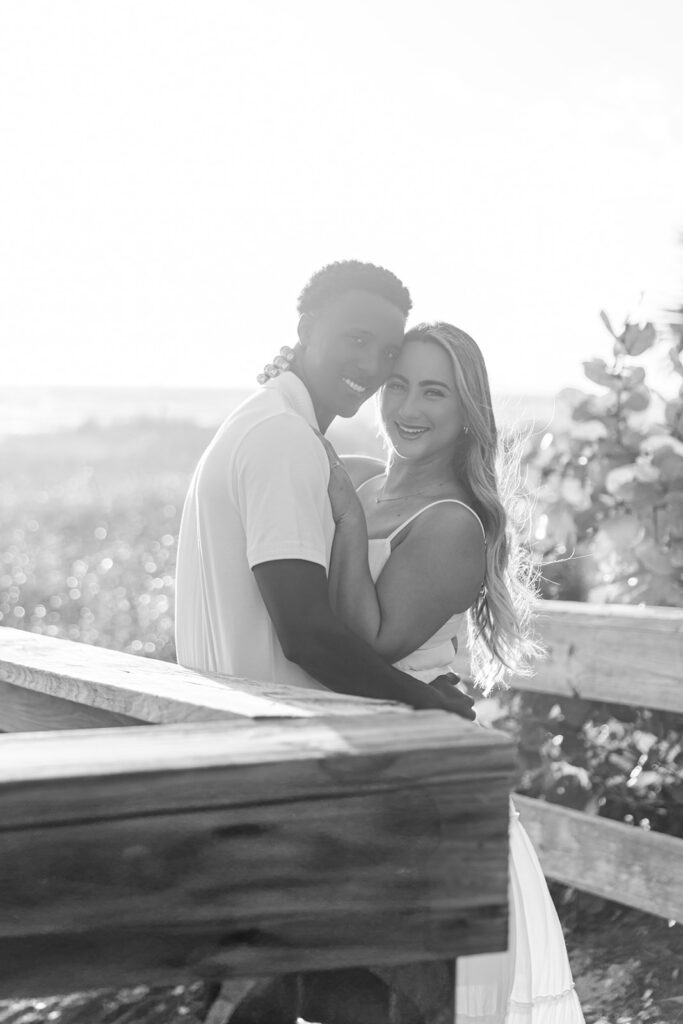 couple wearing white embrace against the sunrise in a beach engagement photo at Jetty Park Beach in Cape Canaveral, Florida, captured by Snapshots by Gabriela