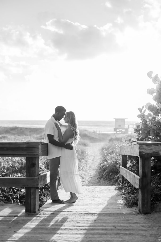 couple wearing white embrace against the sunrise in a beach engagement photo at Jetty Park Beach in Cape Canaveral, Florida, captured by Snapshots by Gabriela