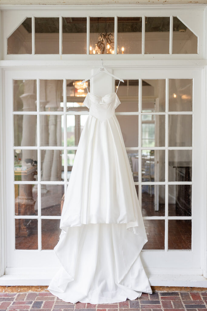 white bridal gown hancing from a window at a wedding at Bella Cosa Lakeside in Lake Wales Florida