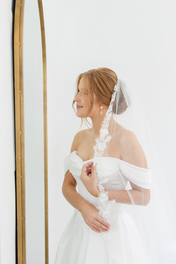 bride looking in the mirrow dressed in her bridal gown and veil at a wedding at Bella Cosa Lakeside in Lake Wales Florida