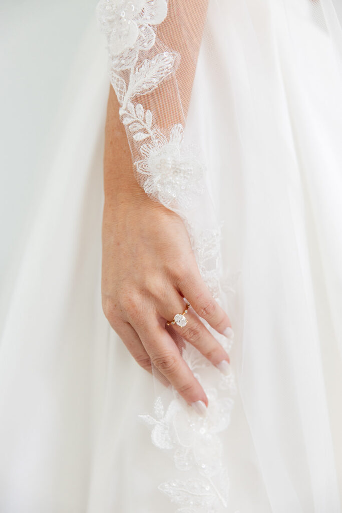 bride's hand touching a floral lace veil wearing a wedding ring at a wedding at Bella Cosa Lakeside in Lake Wales Florida