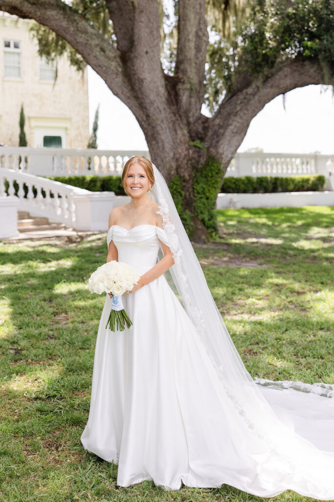 bride posing in her bridal gown and veil holding a white rose bouquet at a wedding at Bella Cosa Lakeside in Lake Wales Florida