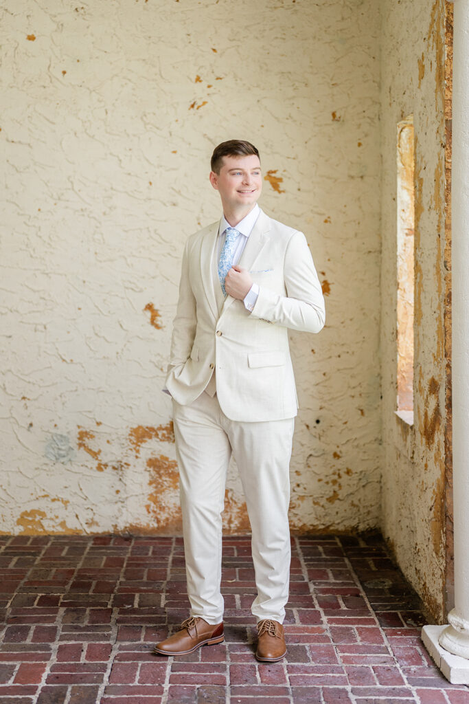 groom wearing a tan linen suit with blue floral tie at a wedding at Bella Cosa Lakeside in Lake Wales Florida