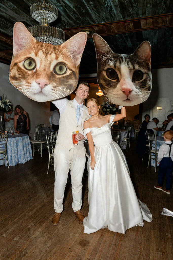 bride and groom hold cat cut-outs at a wedding reception at Bella Cosa Lakeside in Lake Wales Florida