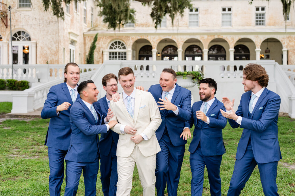 groom in tan linen suit walking on the lawn with groomsmen in blue suits at a wedding at Bella Cosa Lakeside in Lake Wales Florida