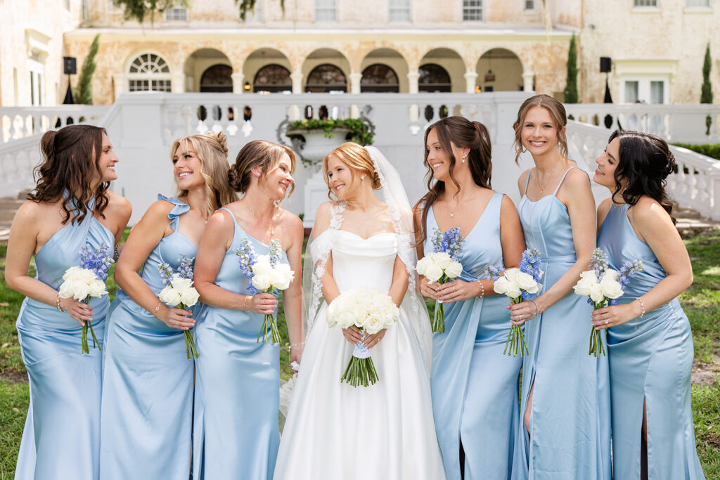 bride in white with bridesmaids in blue dresses posing at a wedding at Bella Cosa Lakeside in Lake Wales Florida