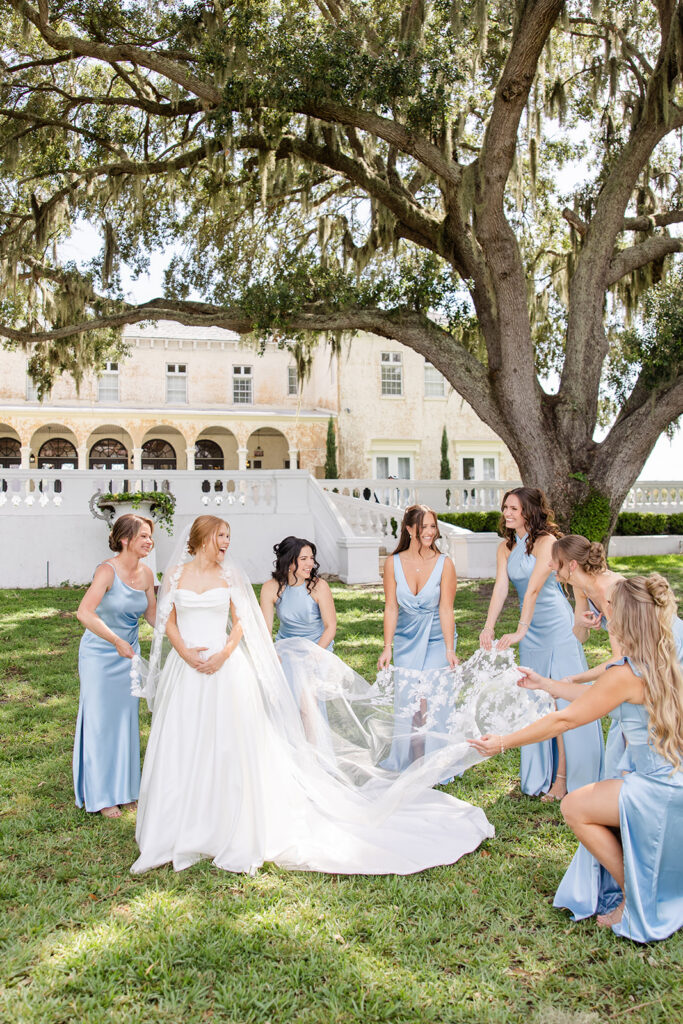 bride walking on the lawn with bridesmaids in blue dresses at a wedding at Bella Cosa Lakeside in Lake Wales Florida