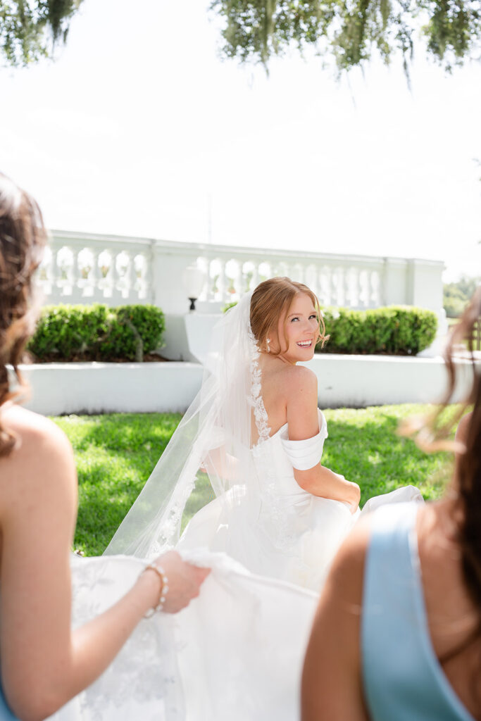 bride walking on the lawn with bridesmaids in blue dresses at a wedding at Bella Cosa Lakeside in Lake Wales Florida