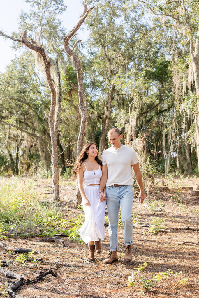 Couple poses naturally in front of trees in a casual engagement photo at Bok Tower Gardens captured by Snapshots by Gabriela.