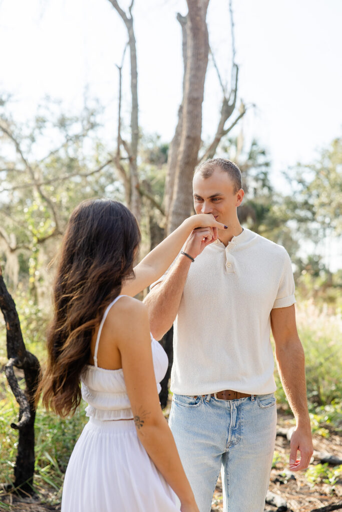 Man kisses woman's hand in a casual engagement photo at Bok Tower Gardens captured by Snapshots by Gabriela.