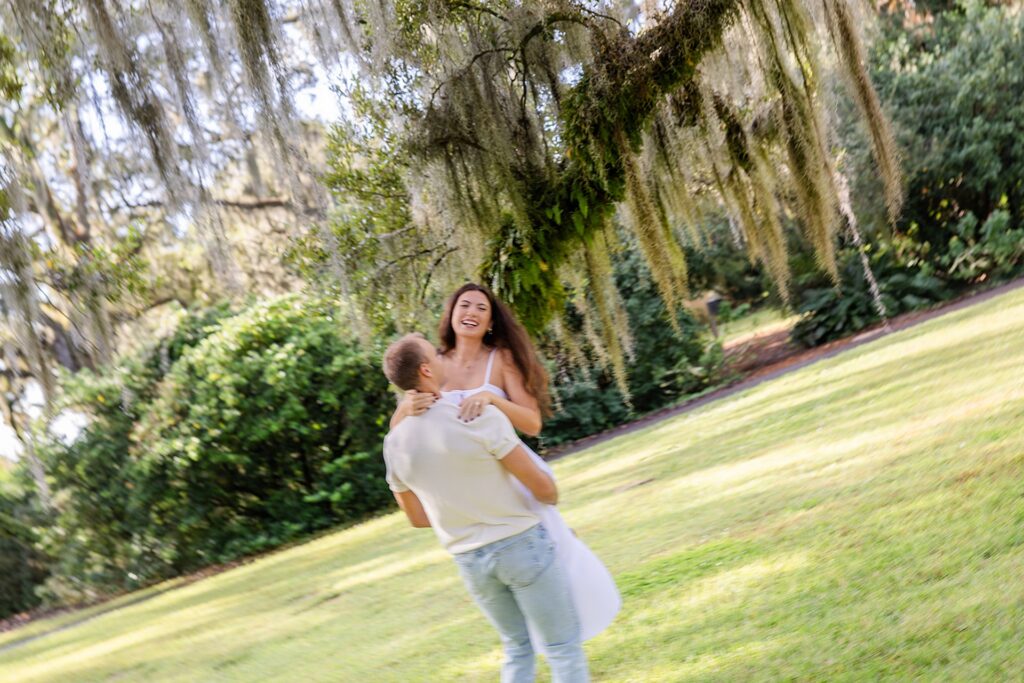 couple dances and twirls in a fuzzy engagement photo at Bok Tower Gardens captured by Snapshots by Gabriela.