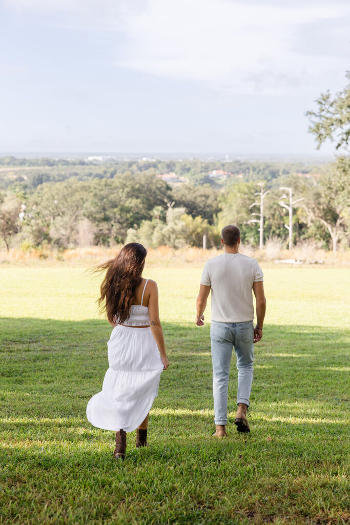 couple walks on a grassy lawn in a casual engagement photo at Bok Tower Gardens captured by Snapshots by Gabriela.