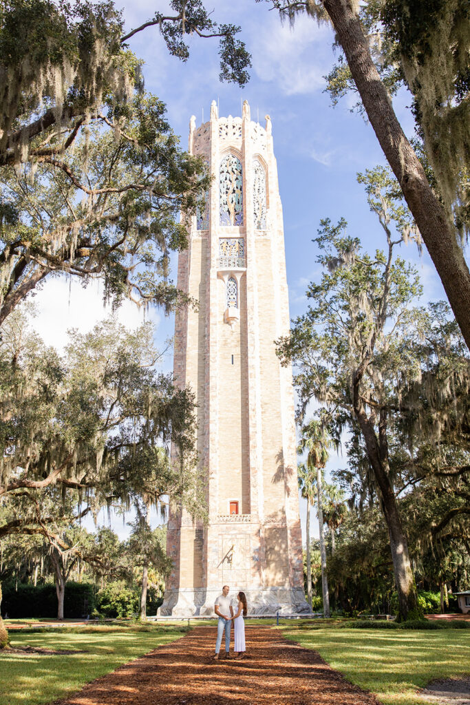 couple stands in front of the Singing Tower in a casual engagement photo at Bok Tower Gardens captured by Snapshots by Gabriela.