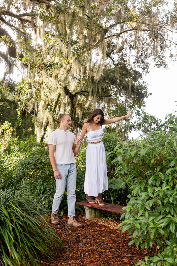 couple walks down a nature path in a casual engagement photo at Bok Tower Gardens captured by Snapshots by Gabriela.