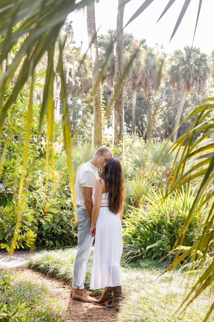 couple kisses on a nature path in a casual engagement photo at Bok Tower Gardens captured by Snapshots by Gabriela.