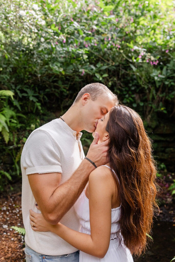 couple kisses on a nature path in a casual engagement photo at Bok Tower Gardens captured by Snapshots by Gabriela.