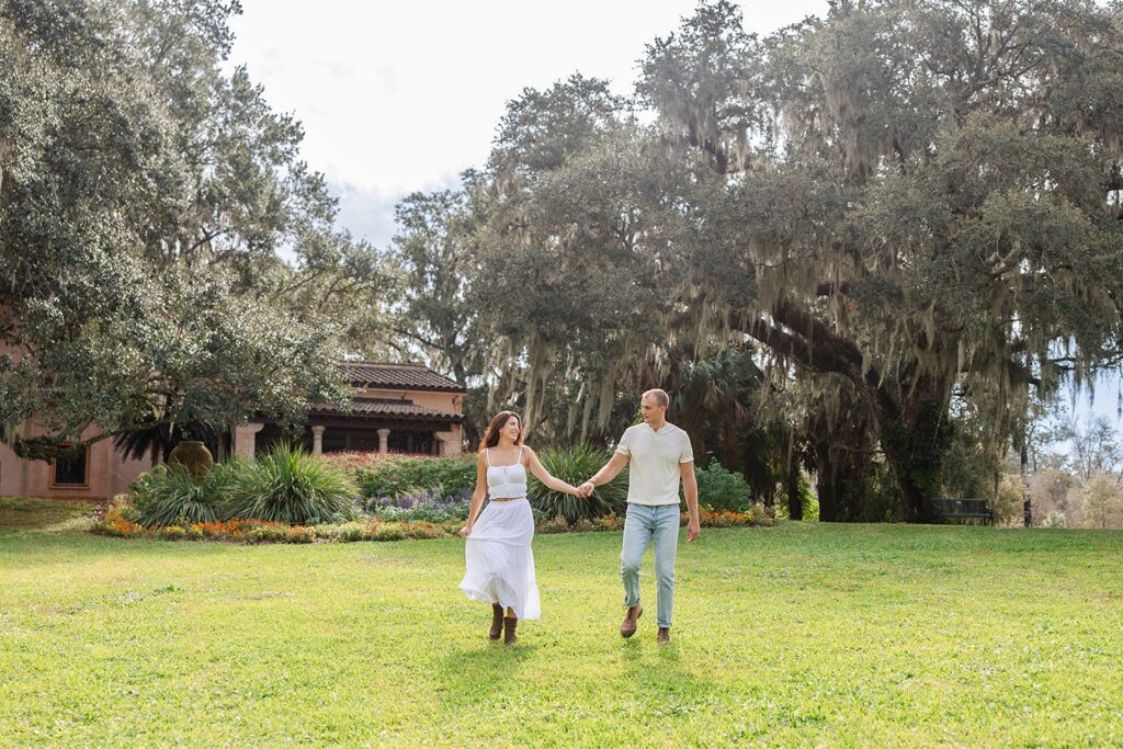 couple walks on a grassy lawn in a casual engagement photo at Bok Tower Gardens captured by Snapshots by Gabriela.