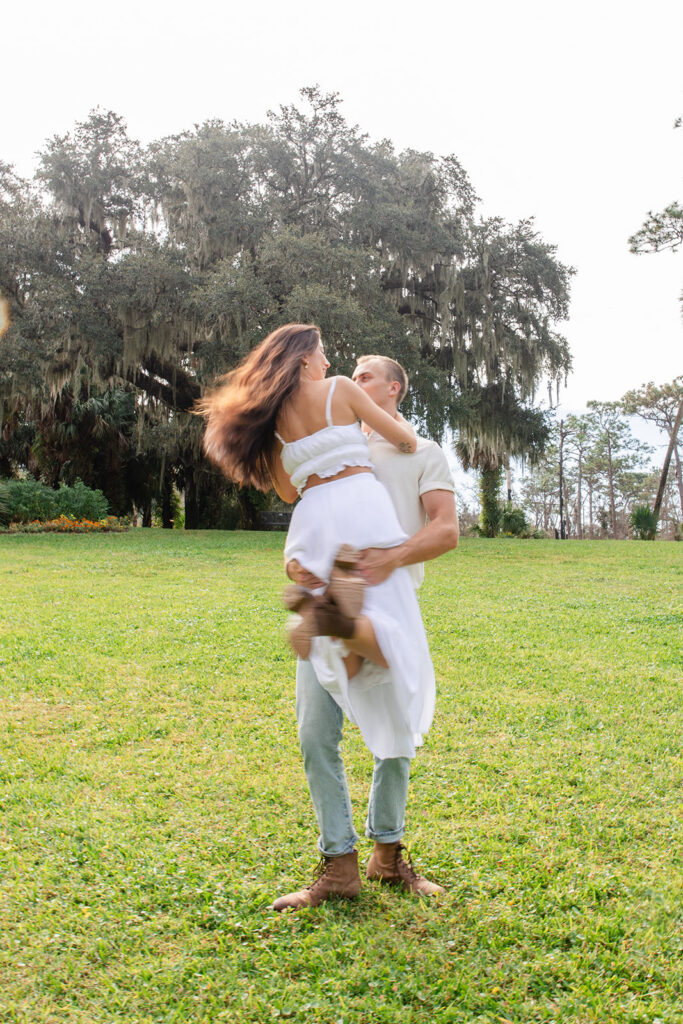 couple dances and twirls in a casual engagement photo at Bok Tower Gardens captured by Snapshots by Gabriela.