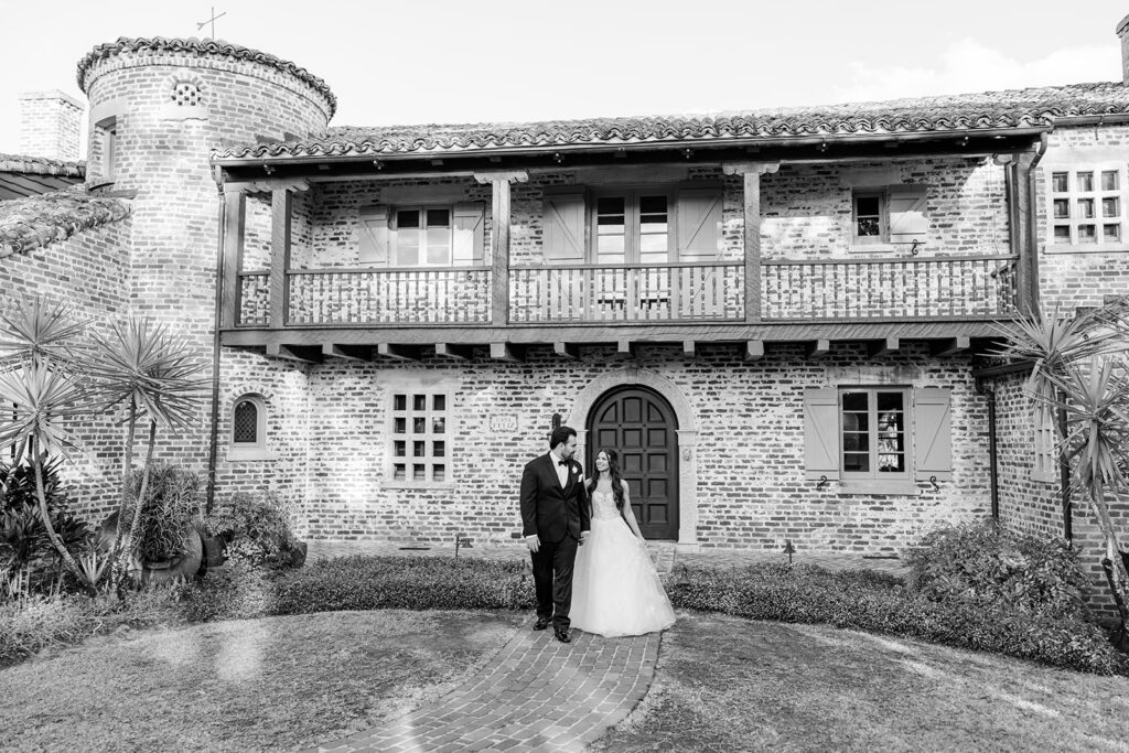 black and white wide shot of bride and groom in front of historic estate wedding venue Casa Feliz in Winter Park, Florida, photographed by Snapshots by Gabriela