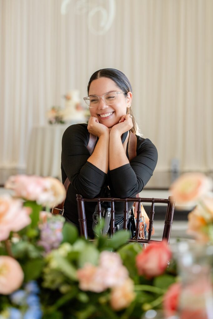 a behind-the-scenes photo of Gabriela from Snapshots by Gabriela, an Orlando wedding photographer, posing playfully by a reception table