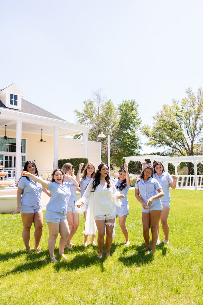 bride and bridesmaids in pajamas walk candidly on the lakefront lawn at a spring wedding at Lake Mary Events Center, captured by Snapshots by Gabriela