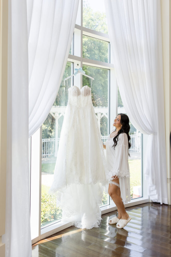 bride in white robe stands in front of her gown at a spring wedding at Lake Mary Events Center, captured by Snapshots by Gabriela