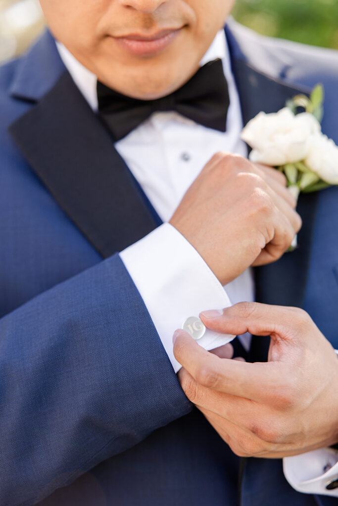 groom in navy suit holding cufflink at a spring wedding at Lake Mary Events Center, captured by Snapshots by Gabriela