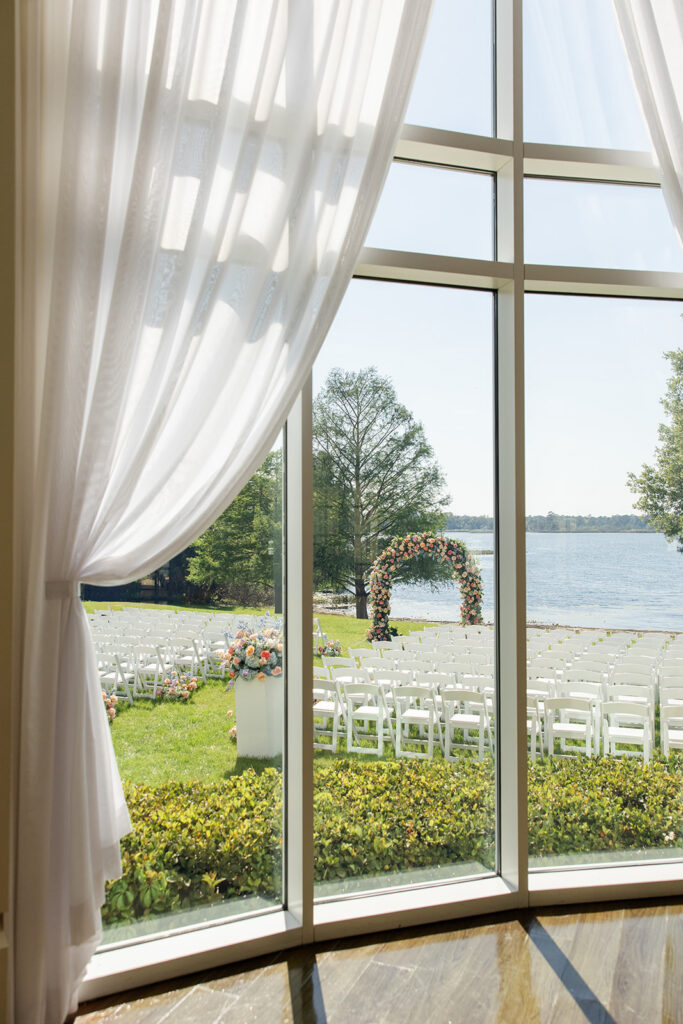 outdoor wedding ceremony setup with spring flowers shot through a window at Lake Mary Events Center, captured by Snapshots by Gabriela