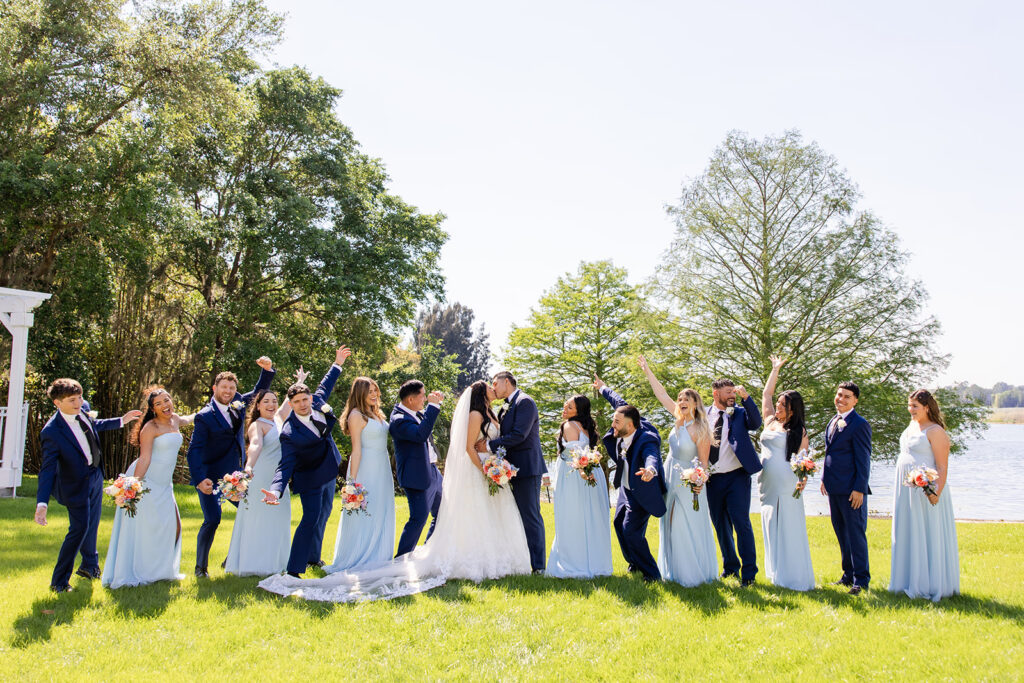wedding party surrounding bride and groom kissing at a spring wedding at Lake Mary Events Center, captured by Snapshots by Gabriela
