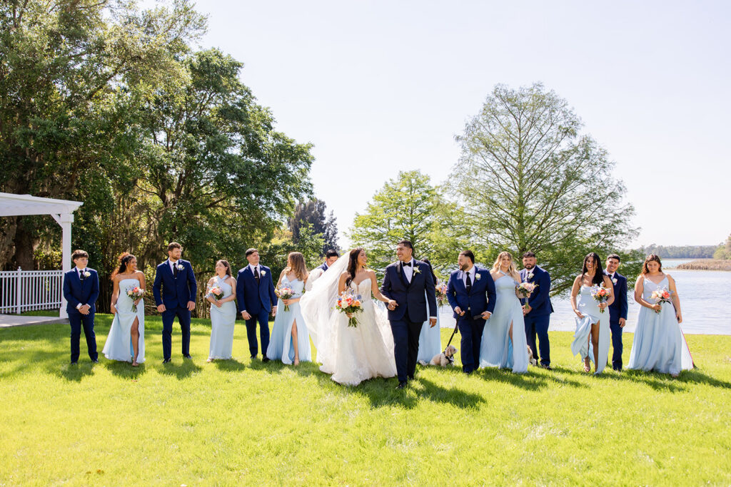 wedding party walks candidly on the lakefront lawn at a spring wedding at Lake Mary Events Center, captured by Snapshots by Gabriela