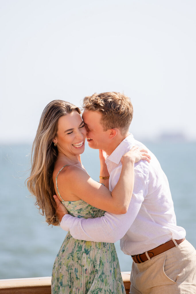 Woman in green floral dress and man in white shirt and khaki pants overlooking the water at The Ringling Museum in Sarasota for their engagement photos captured by Snapshots by Gabriela